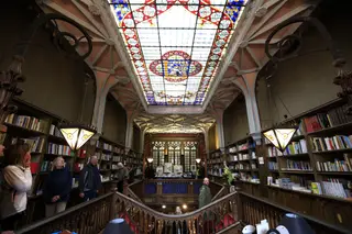No centro do teto da Livraria Lello está um enorme vitral com a divisa "Decus in Labore"