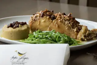 O bacalhau à Papa-Figos, confitado, com crosta de frutos secos e mel, acompanhado com feijão-verde salteado e puré de grão é um dos pratos emblemáticos