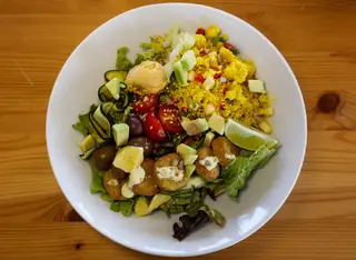 Falafel com cuscuz, abacate, curgete, azeitonas, húmus, sementes tostadas, alface, rúcula e tomate
