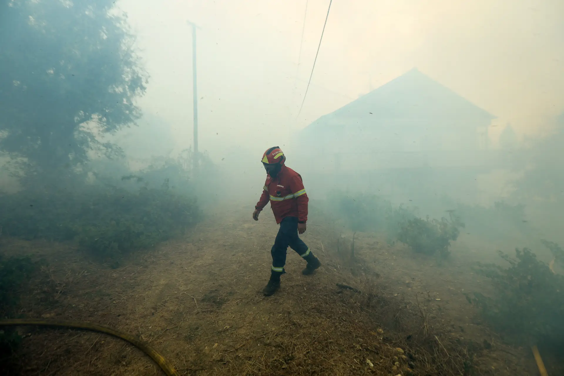 Um bombeiro junto de casas na aldeia de Carreira do Mato (Abrantes) que foi cercada pelo fogo na manhã do dia 10 de agosto de 2017