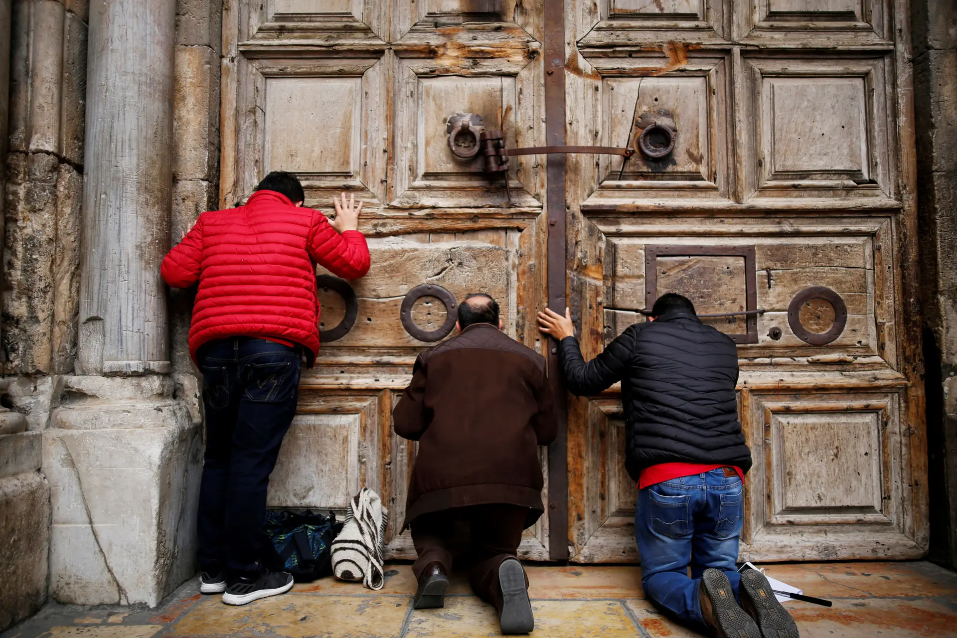Peregrinos em oração junto à porta de entrada do Santo Sepulcro, encerrado no domingo por tempo indefinido