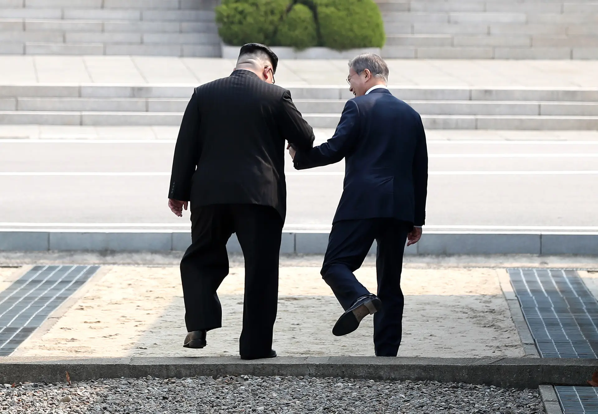 O momento exato em que o Presidente da Coreia do Norte, Kim Jong-un, piso solo sul-coreano. De mãos dadas com o Presidente da Coreia do Sul, Moon Jae-in, atravessou a zona de divisão dos dois países.