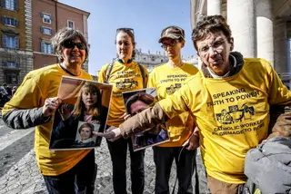 Manifestantes com fotos de vítimas de abuso junto à Basílica de São Pedro, esta quinta-feira de manhã no Vaticano <span class="creditofoto">Foto GIUSEPPE LAMIEPA/EPA</span>