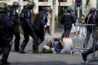 Casal protege-se da polícia após confrontos com manifestantes durante o Dia da Bastilha