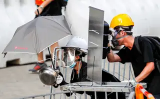 Manifestantes tentam proteger-se do gás lacrimogénio lançada pela polícia de Hong Kong <span class="creditofoto">Foto Kim Kyung-Hoon / Reuters</span>