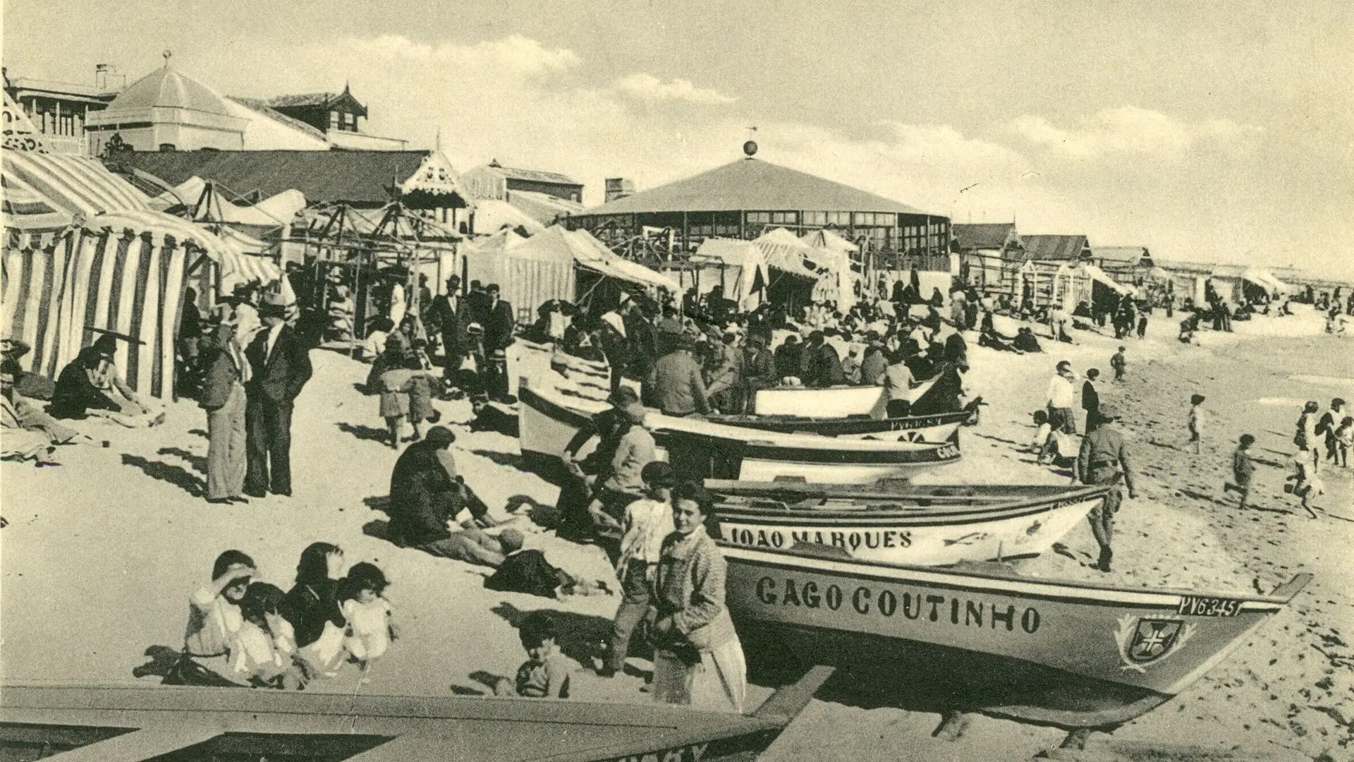 Praia de Póvoa de Varzim. Habitantes do Minho em uso de banho ou de ar do mar.Pequenos barcos de pesca à beira-mar