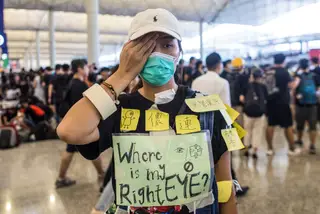 Uma manifestante solidária com a mulher ferida no domingo tapa um olho e pergunta: “Onde está o meu olho direito?” <span class="creditofoto">Foto Jerome Favre / EPA</span>