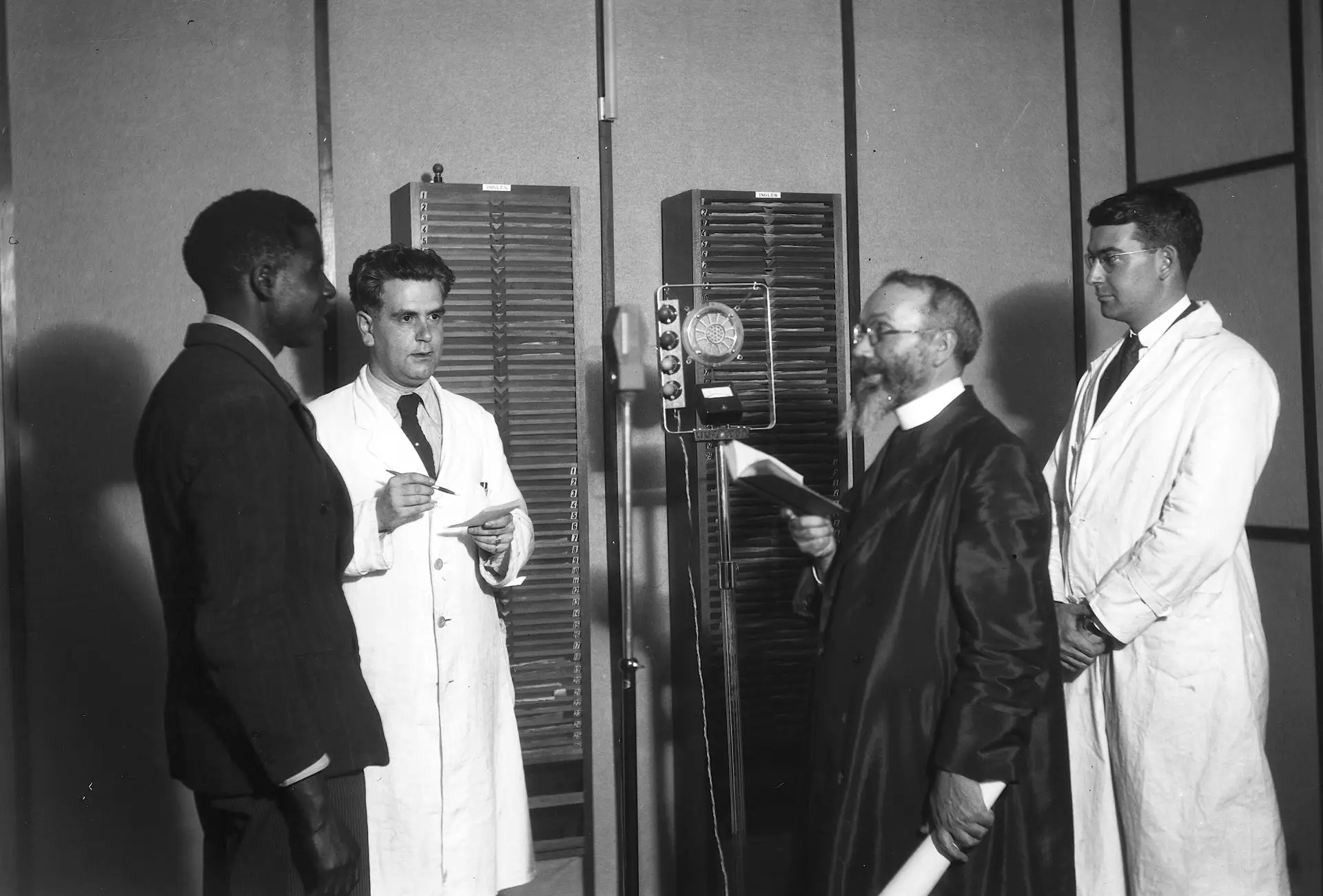 Gravação de discos em quimbundo no Laboratório de Fonética Experimental da Universidade de Coimbra, em 1939. Da esquerda para a direita: Mateus (locutor em quimbundo), Armando de Lacerda, Padre Domingos Baião (locutor em português) e o investigador da Universidade de Harvard, Francis M. Rogers