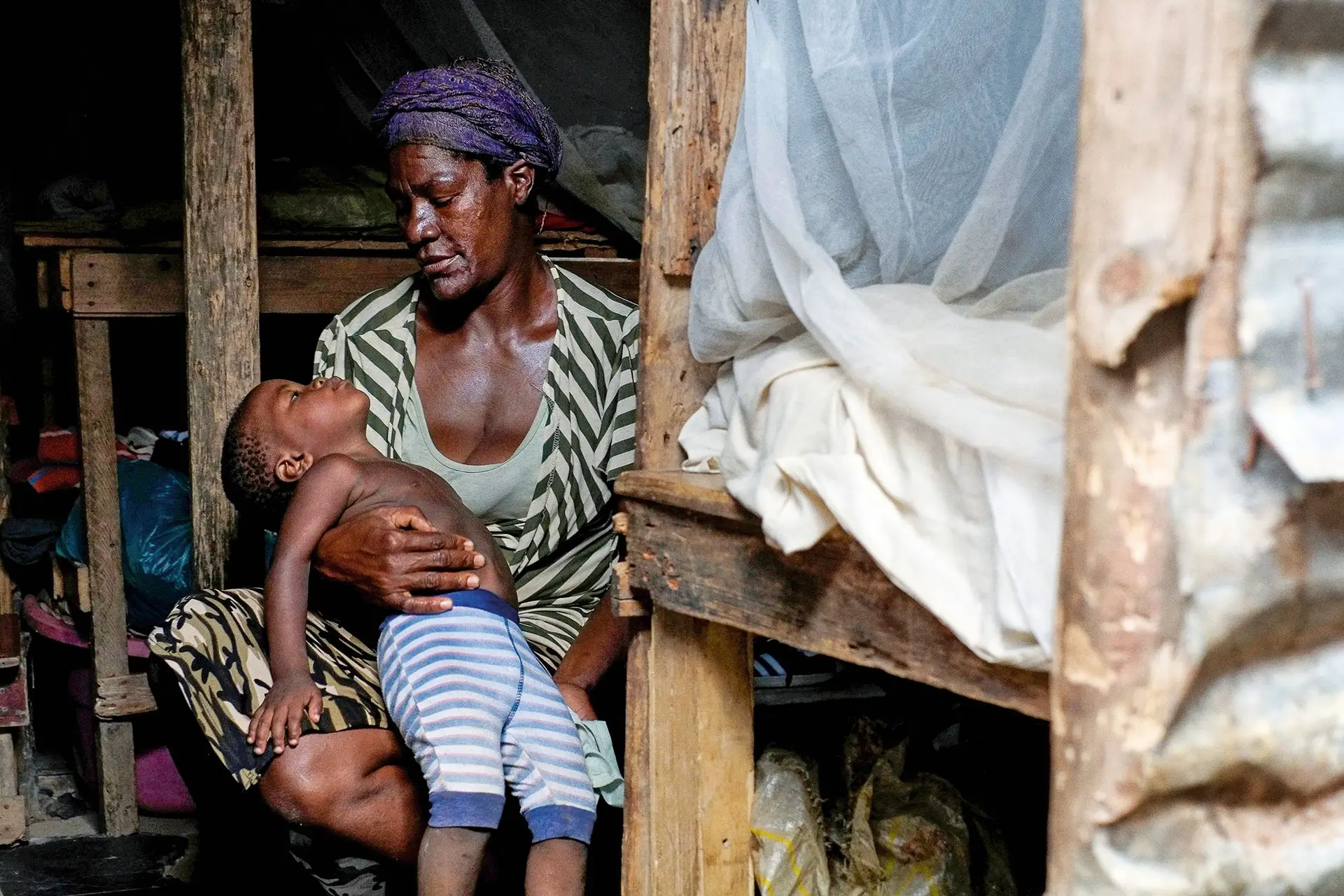 Albertina de Fátima, com um dos seus netos, na barraca que partilha com mais quatro famílias, no Povoado, a cinco minutos do centro de Luanda
