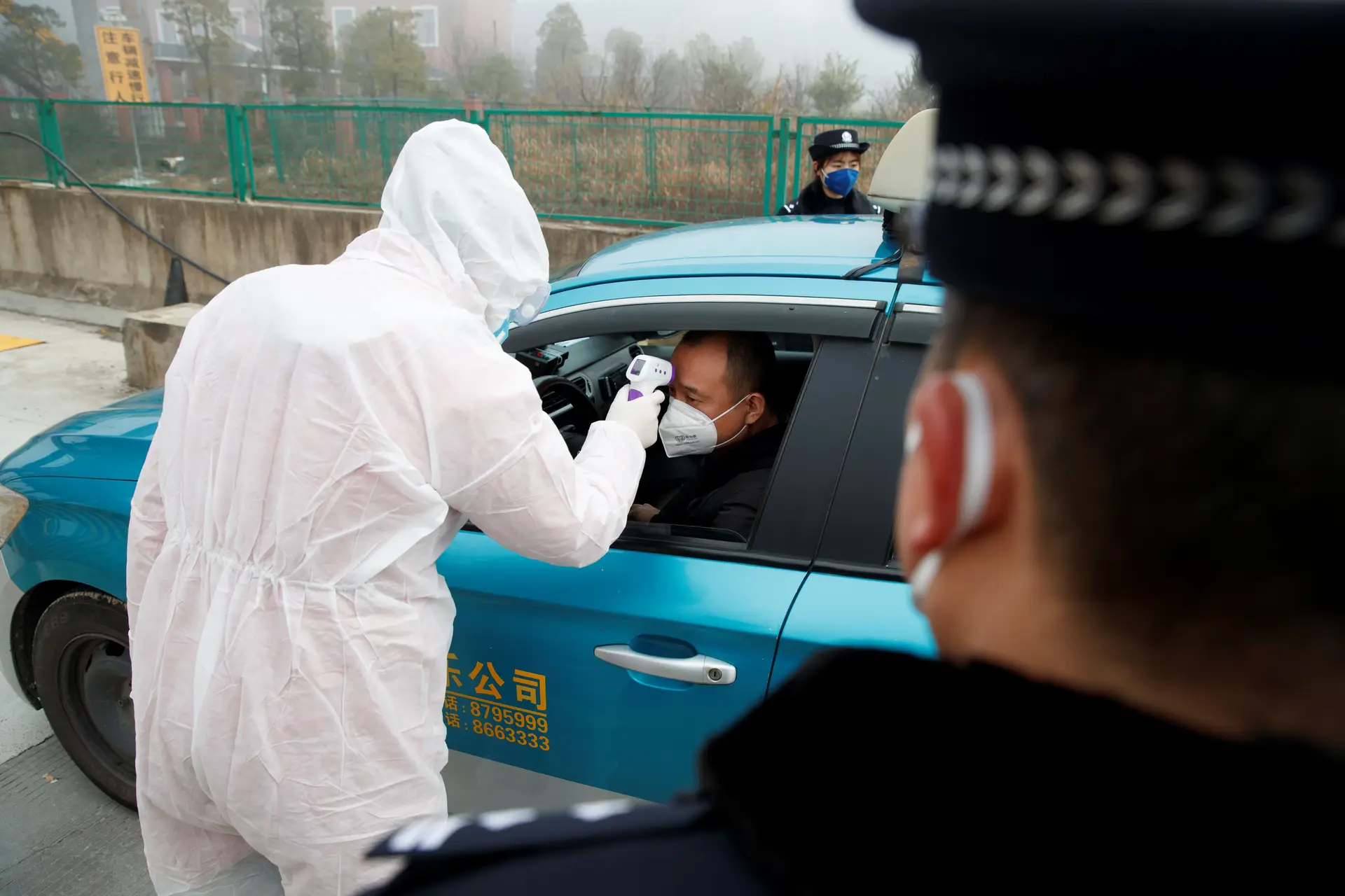 Um médico verifica a temperatura de um cidadão num checkpoint à entrada de Yueyang