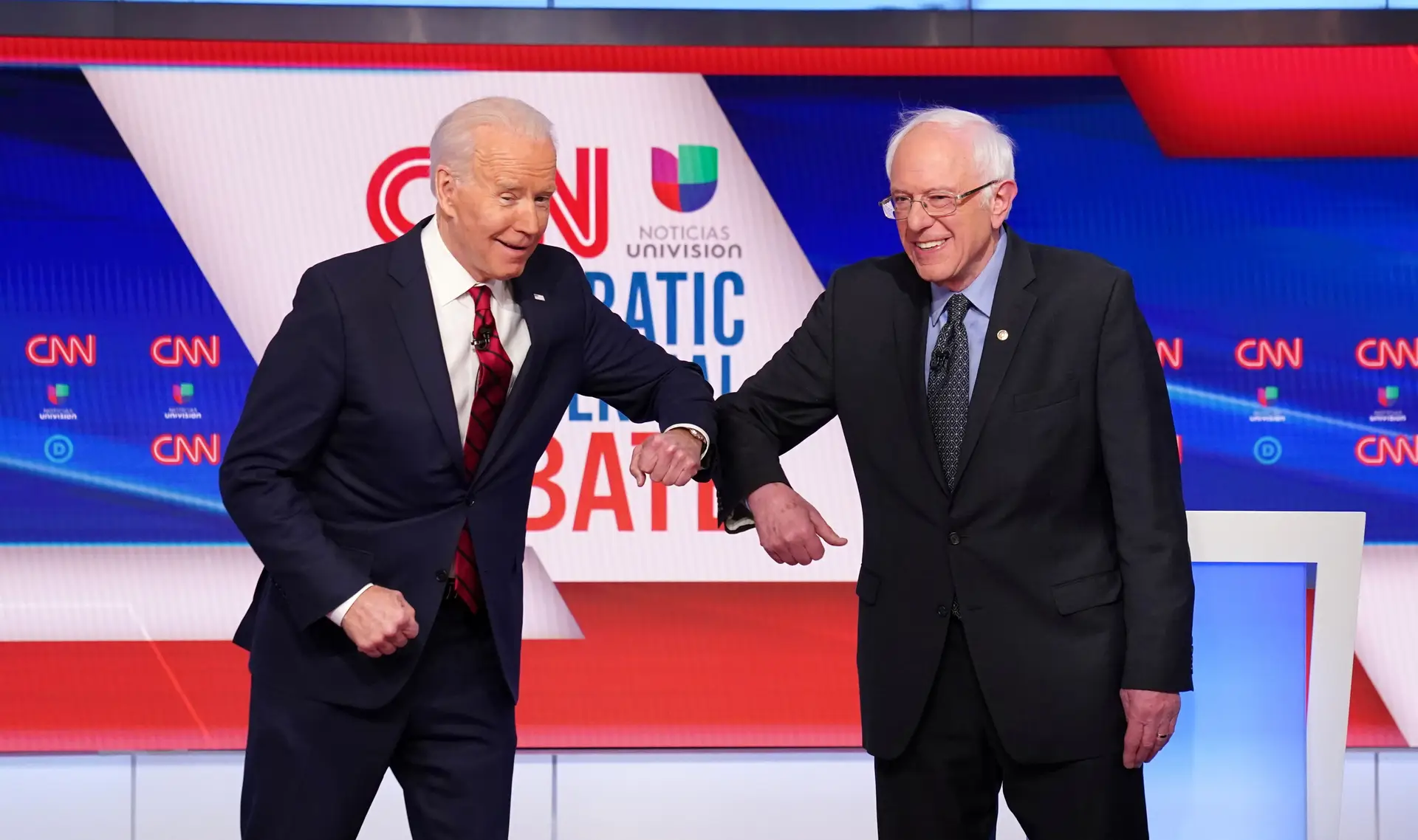 Joe Biden e Bernie Sanders cumprimentam-se com o cotovelo no arranque do 11.º debate das primárias democratas, em Washington, este domingo