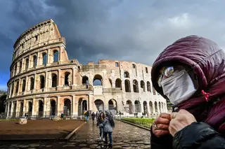 <span class="arranque"><span style="color:#d0b667">Medo</span></span> Um homem com uma máscara passa junto ao Coliseu de Roma. A Itália é um dos países mais atingidos pela pandemia de Covid-19 <span class="creditofoto">Alberto PIZZOLI/AFP</span>