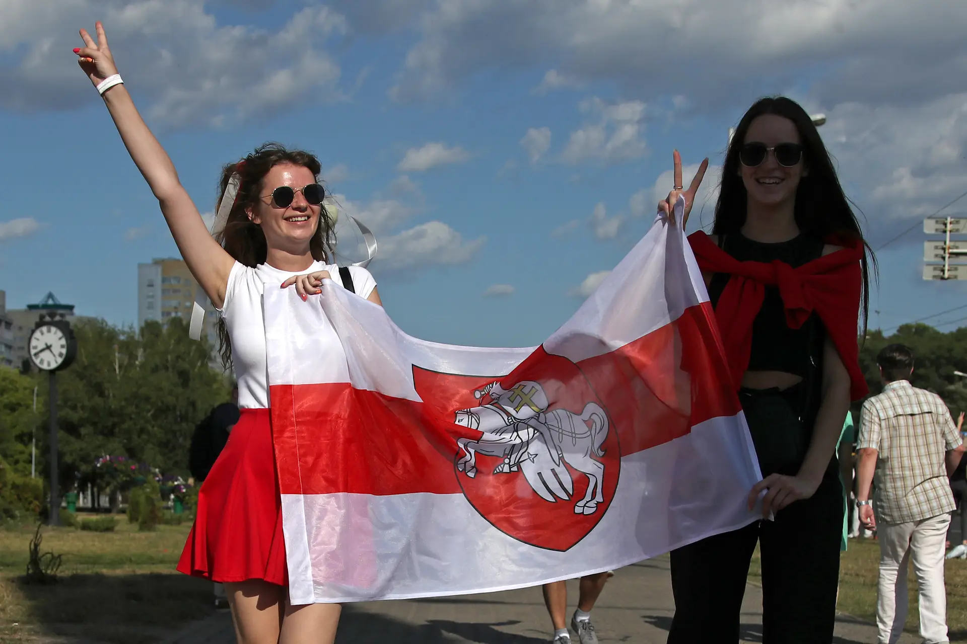 Duas mulheres ostentam uma antiga bandeira da Bielorrússia, do período entre 1991 e 1995, em protesto, nas ruas de Minsk
