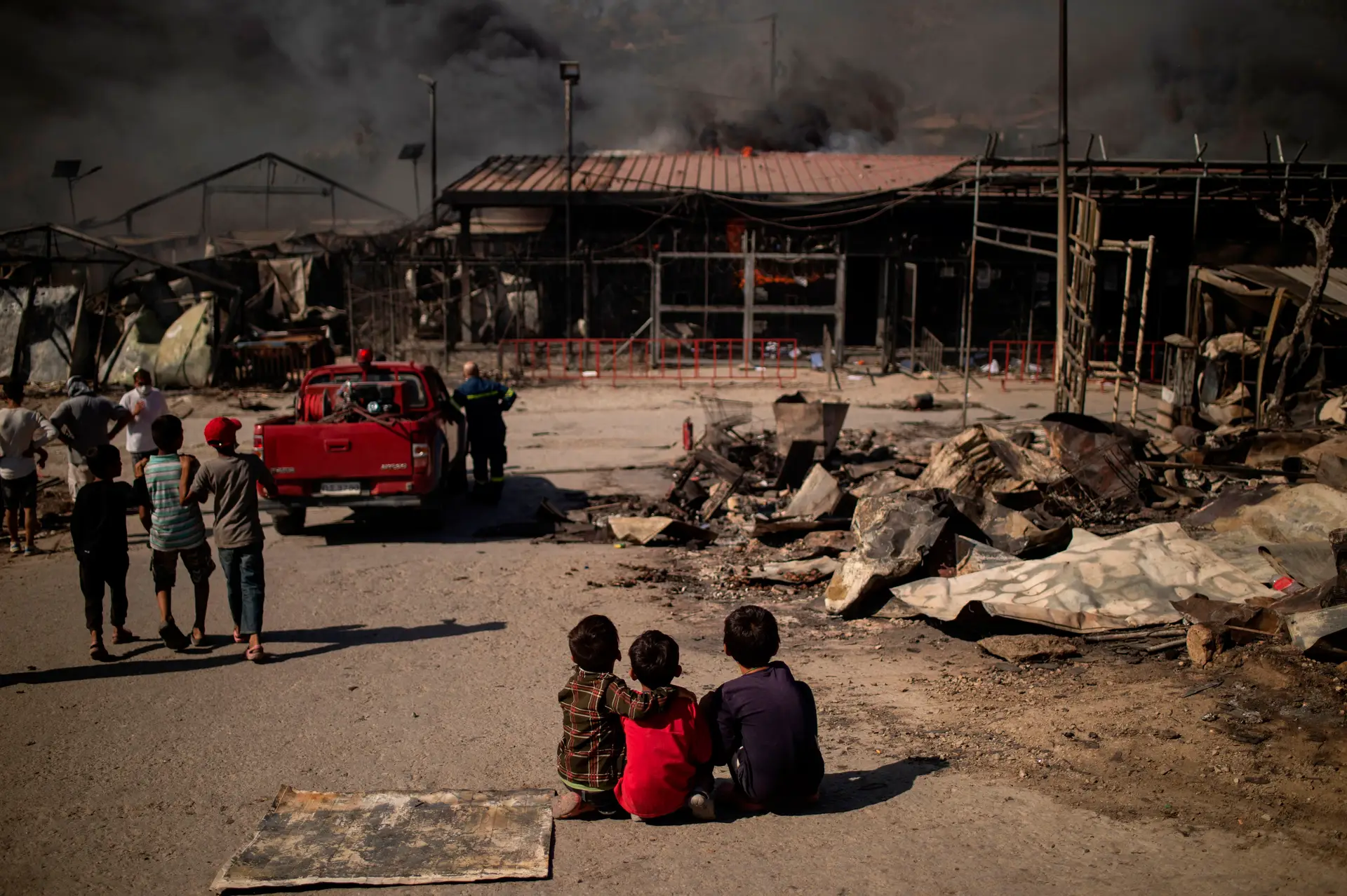 Crianças observam à distância a destruição do local a que chamavam “casa”