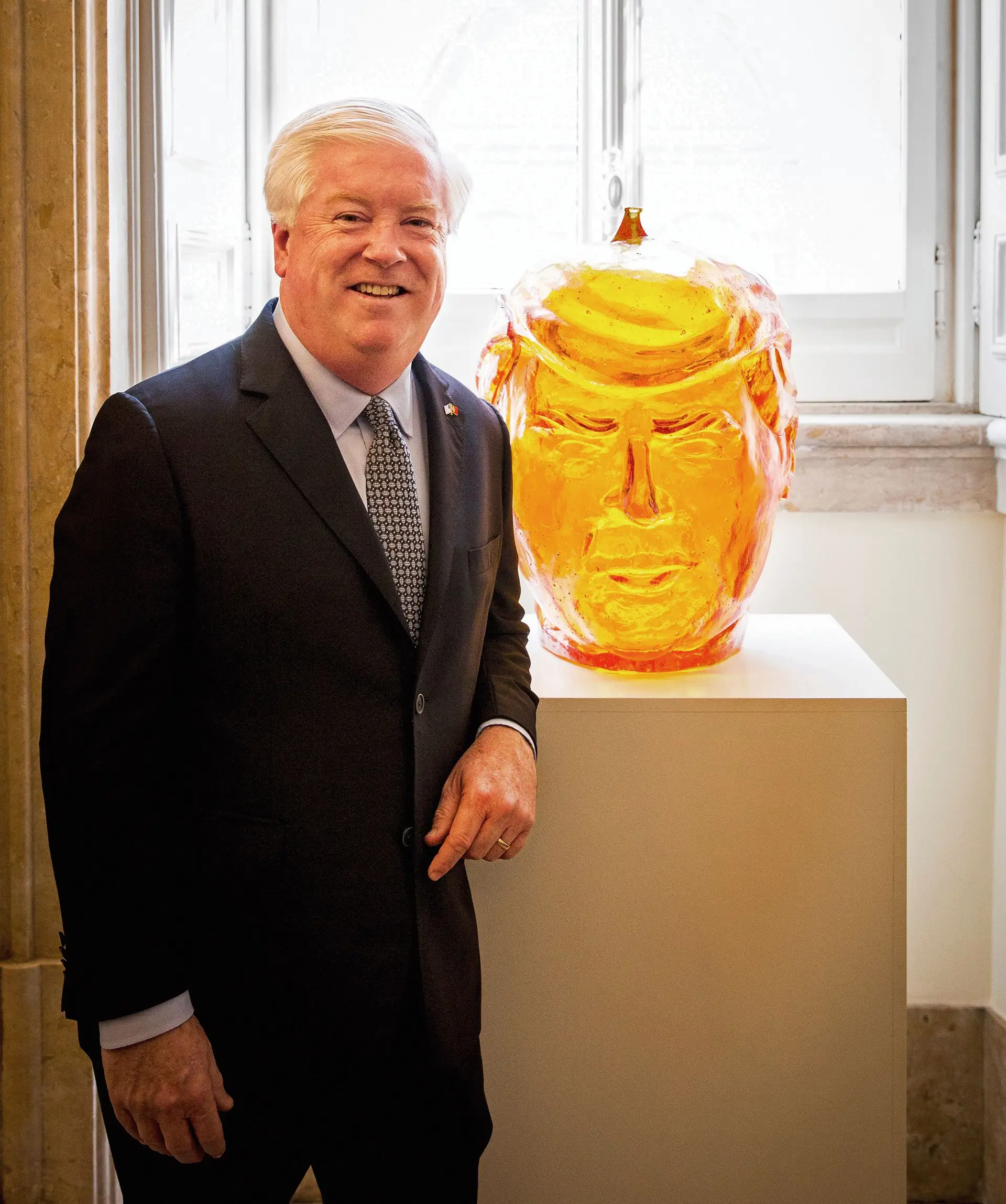 George Glass, fotografado esta segunda-feira na Casa Carlucci, a residência do embaixador norte-americano em Lisboa, junto a “Donald”, uma escultura-mealheiro de Trump do artista Andy Yoder, de 2007
