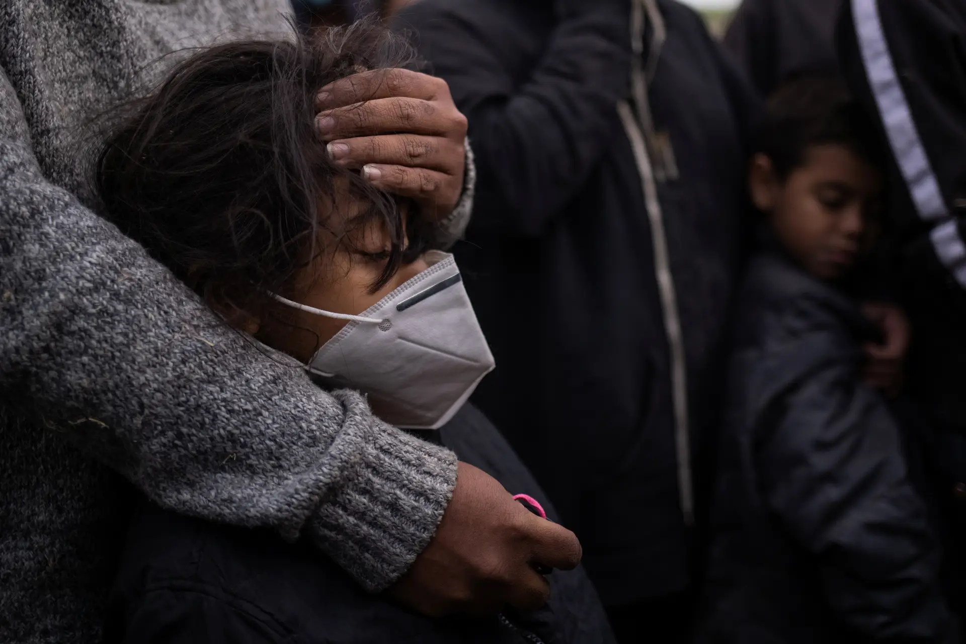 De aspeto adoentado, a pequena Jocelyn, uma hondurenha de seis anos, é confortada pela mãe enquanto espera por transporte da polícia norte-americana. As duas, e dezenas de outros migrantes, acabaram de entrar nos EUA, em jangadas