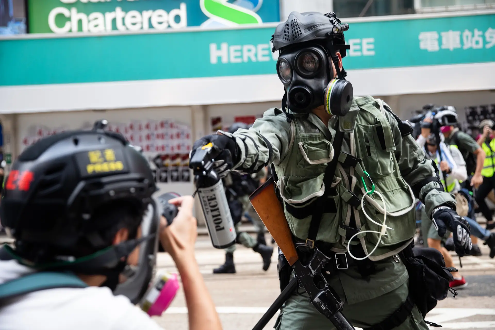 Um agente da polícia de intervenção dispara gás pimenta contra um fotojornalista, que cobre os protestos em Hong Kong