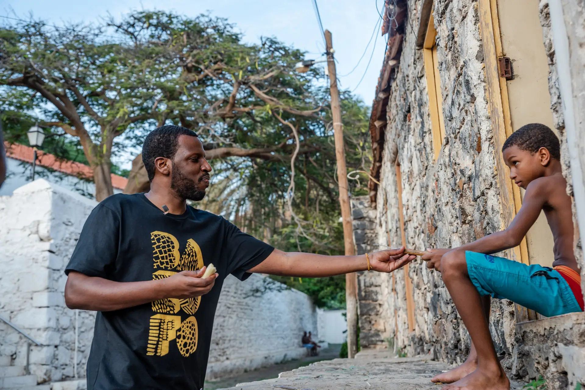 Criança partilha cana de açúcar com Dino D'Santiago, na Rua Banana - Cidade Velha.