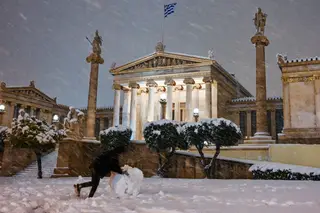GRÉCIA. Sob uma chuva de flocos de neve, este grego aproveita para moldar um boneco, em frente à Academia de Atenas FOTO: Milos Bicanski / Getty Images