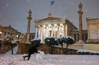 GRÉCIA. Sob uma chuva de flocos de neve, este grego aproveita para moldar um boneco, em frente à Academia de Atenas FOTO: Milos Bicanski / Getty Images