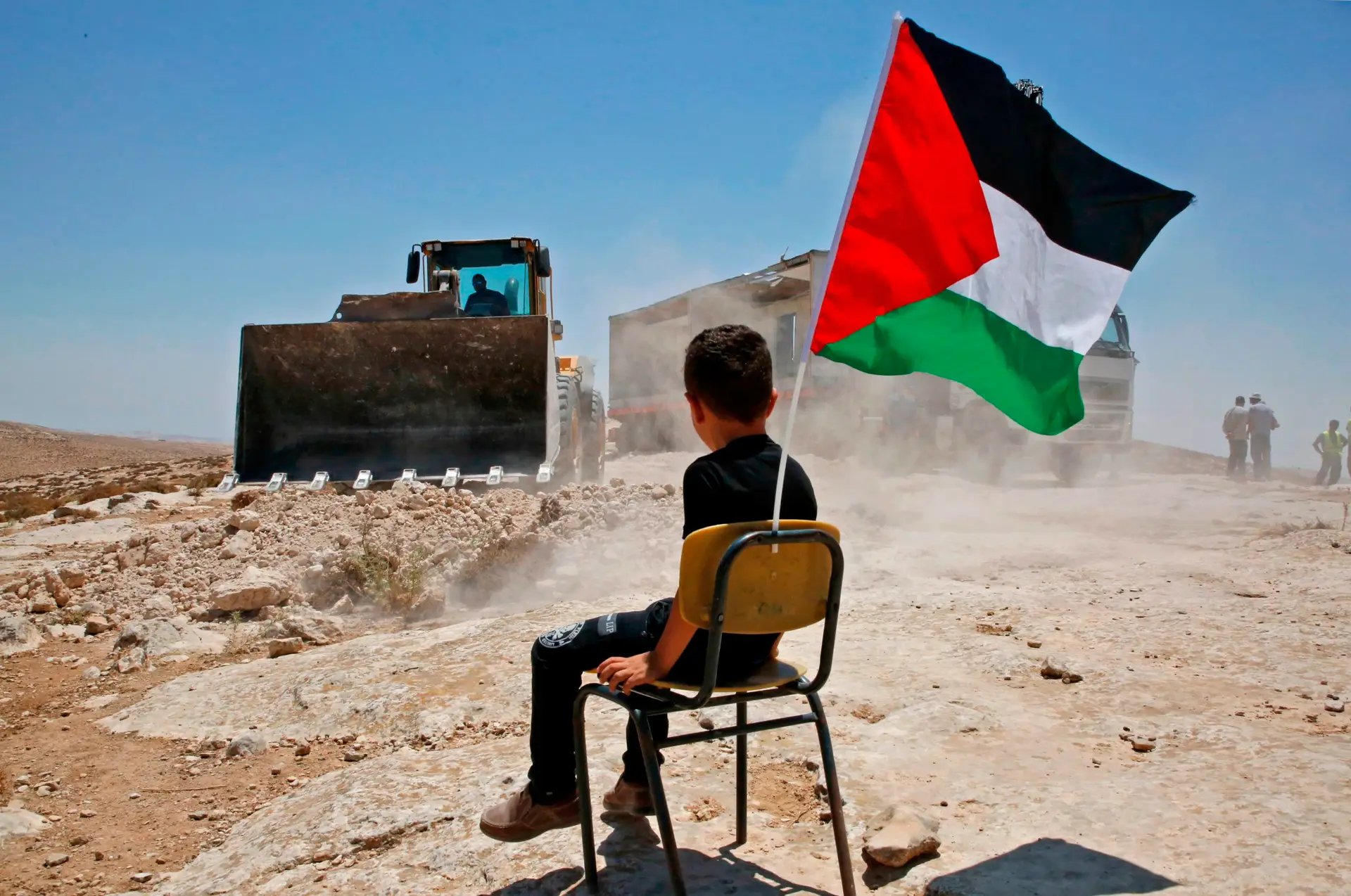 Com a bandeira palestiniana na mão, uma criança observa a demolição da sua escola, na aldeia de Yatta, a sul de Hebron (Cisjordânia) FOTO: Hazem Bader/AFP/Getty Images