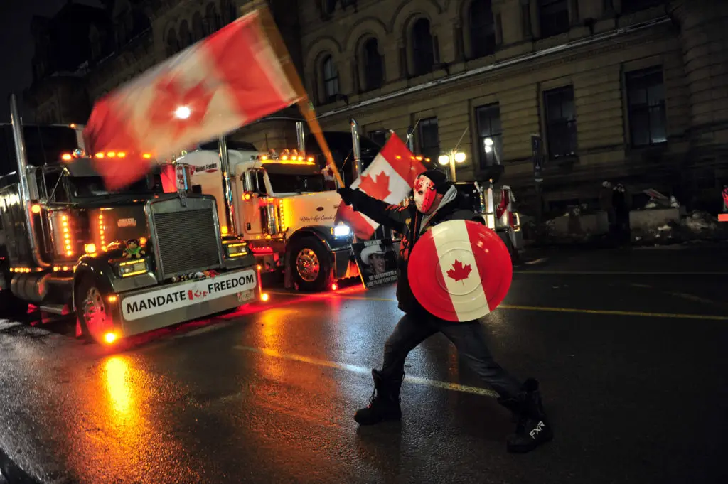 Um camionista em Ottawa com uma bandeira do Canadá a bloquear uma das estradas da capital canadiana. O bloqueio tem provocado o cais nas vias de fornecimento de produtos ente os Estados Unidos e o Canadá e dentro do país FOTO: Kadri Mohamed/Anadolu Agency via Getty Images