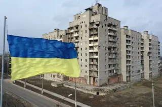 Uma bandeira ucraniana em frente a um edifício danificado nas hostilidades entre forças miitares ucranianas e separatistas russos, que controlam Donetsk e Luhansk, na região de Donbass, no leste da Ucrânia, na fronteira com a Rússia. FOTO: Ali Atmaca/Anadolu Agency/Getty Images