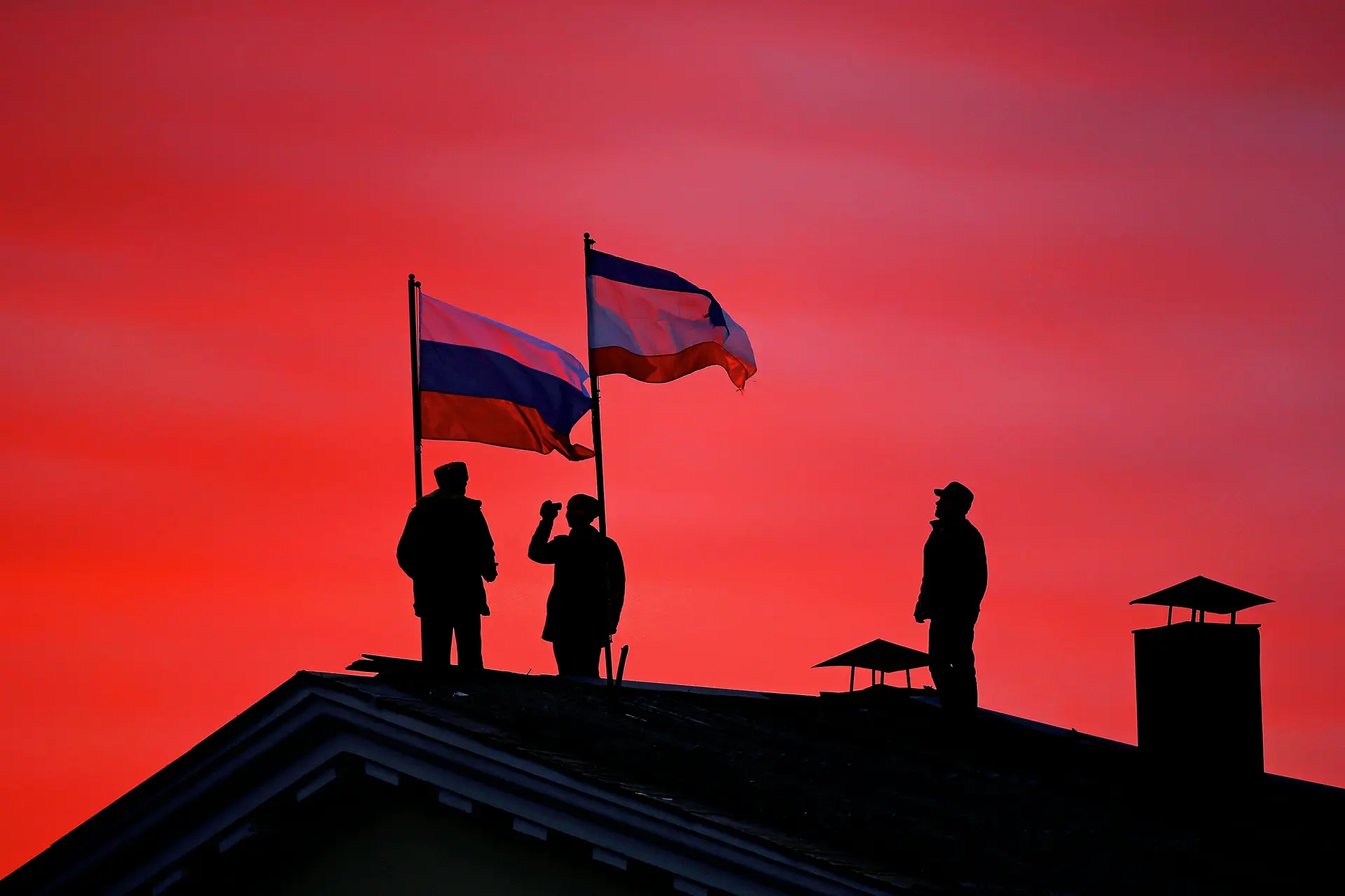 Conquista Cossacos a hastear as bandeiras da Rússia e da Crimeia num edifício governamental em Bakhchysarai, na Ucrânia, a 17 de março de 2014, após um referendo comprovadamente fraudulento ter ditado a anexação da Crimeia à Federação Russa, com 97% de votos a favor