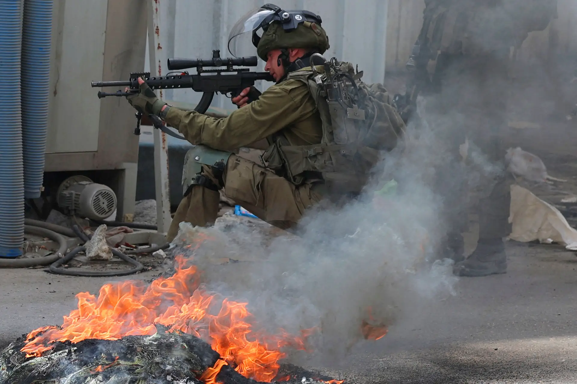 Um soldado israelita aponta a arma durante confrontos com palestinianos, na localidade de Azzun, no norte da Cisjordânia ocupada