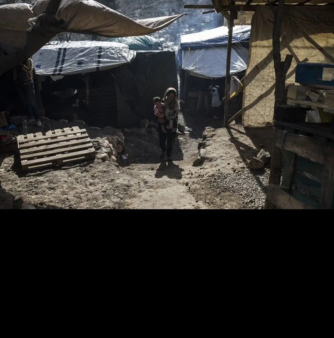 Uma mulher carrega ao colo um bebé no campo de Moria, em Lesbos