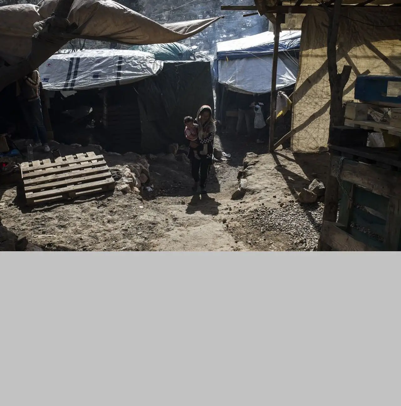 Uma mulher carrega ao colo um bebé no campo de Moria, em Lesbos