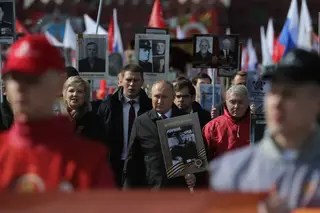 Vladimir Putin displays a portrait of his father during Victory Day in Moscow