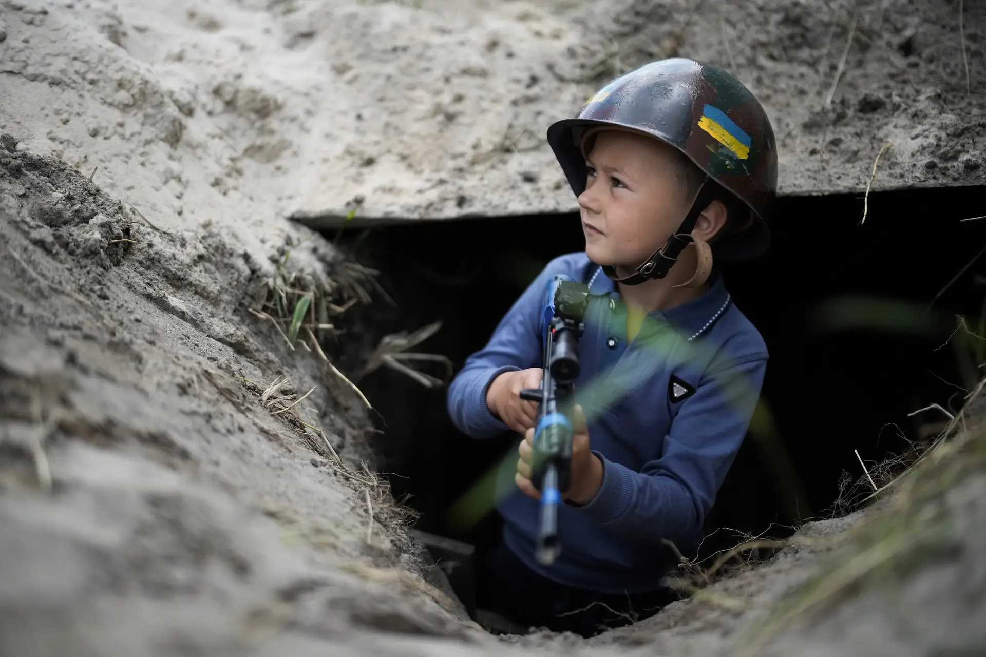 Rapaz de seis anos brinca na trincheira que cavou com os amigos em Stoyanka