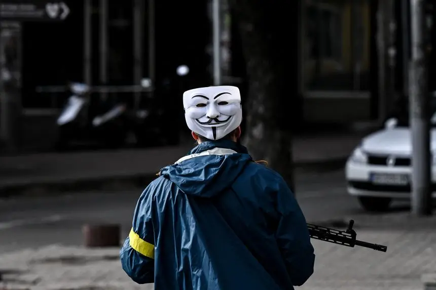  
Ирония как часть войны. Боец украинской теробороны с маской Anonymous на затылке.
