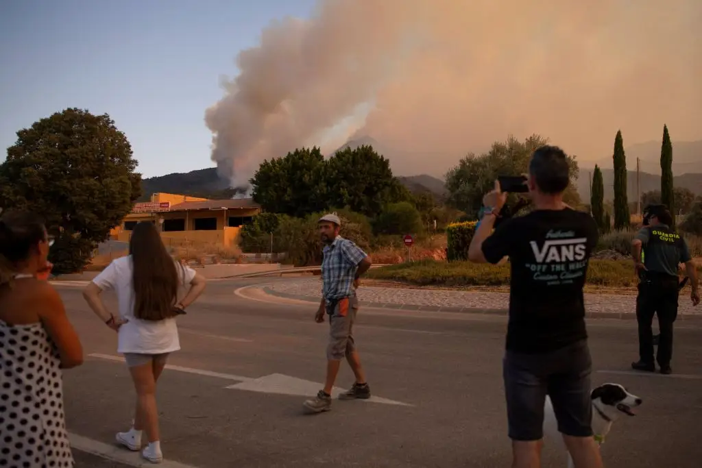 Populares olham para uma nuvem de fumo de um incêndio na Serra de Mijas na província de Málaga, na sexta-feira, dia 15 de julho