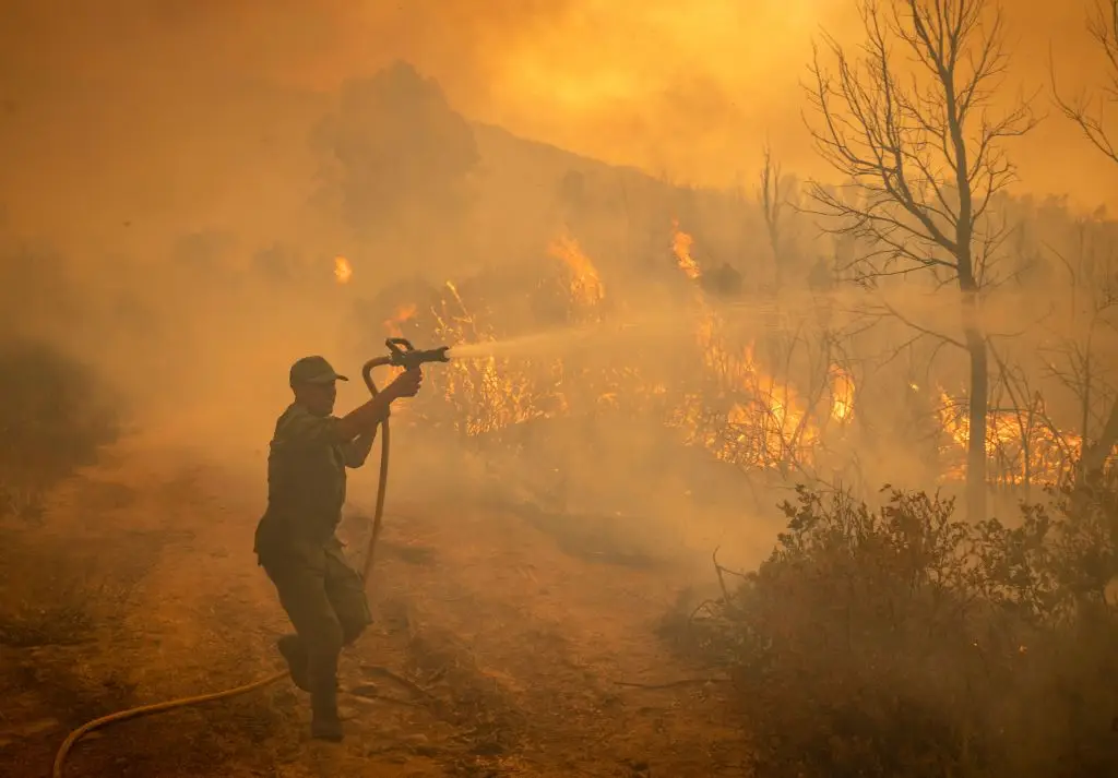 Um soldado marroquino lança água de uma mangueira num incêndio florestal perto da cidade marroquina de Ksar el-Kebir, na região de Larache, a 15 de julho