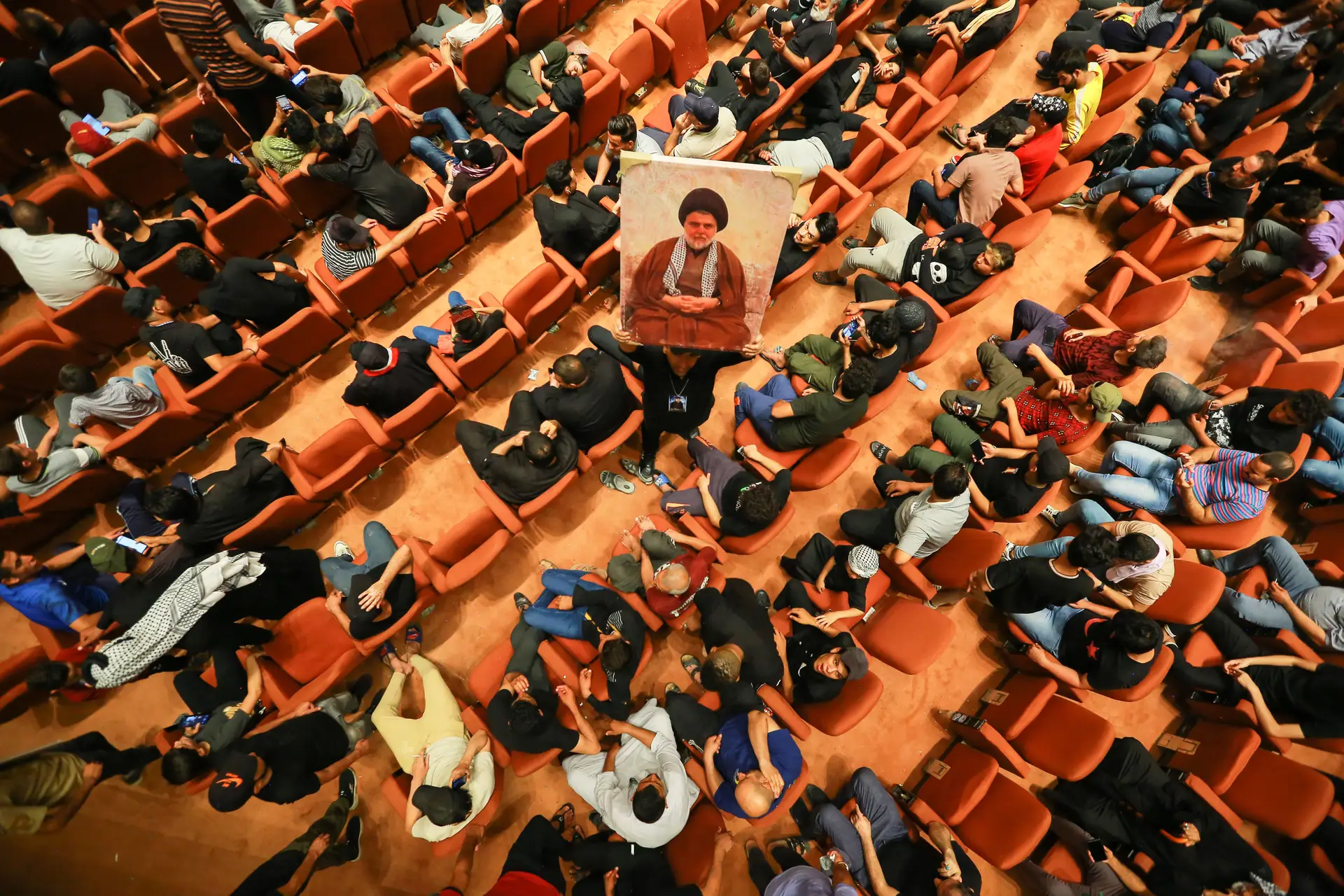 Apoiantes de Muqtada al-Sadr ocupam o Parlamento do Iraque. Um deles, levanta uma fotografia do líder
