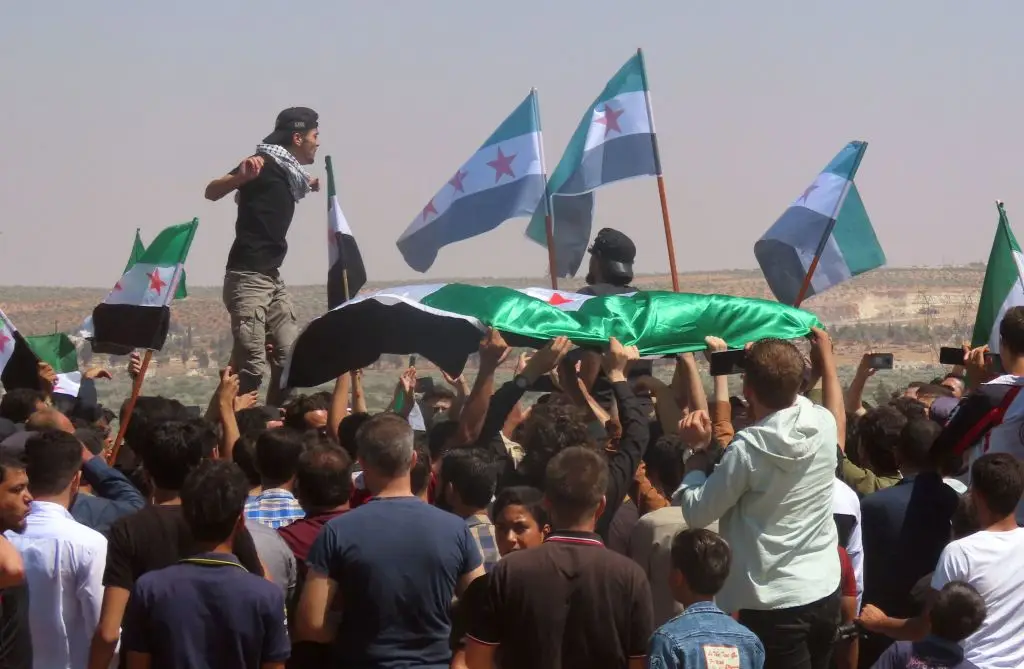 Sírios agitam bandeiras da oposição e protestam na aldeia de al-Mastumah, após as declarações do ministro dos Negócios Estrangeiros turco. Mevlut Çavusoglu falou de uma possível aproximação entre o regime sírio e a Turquia