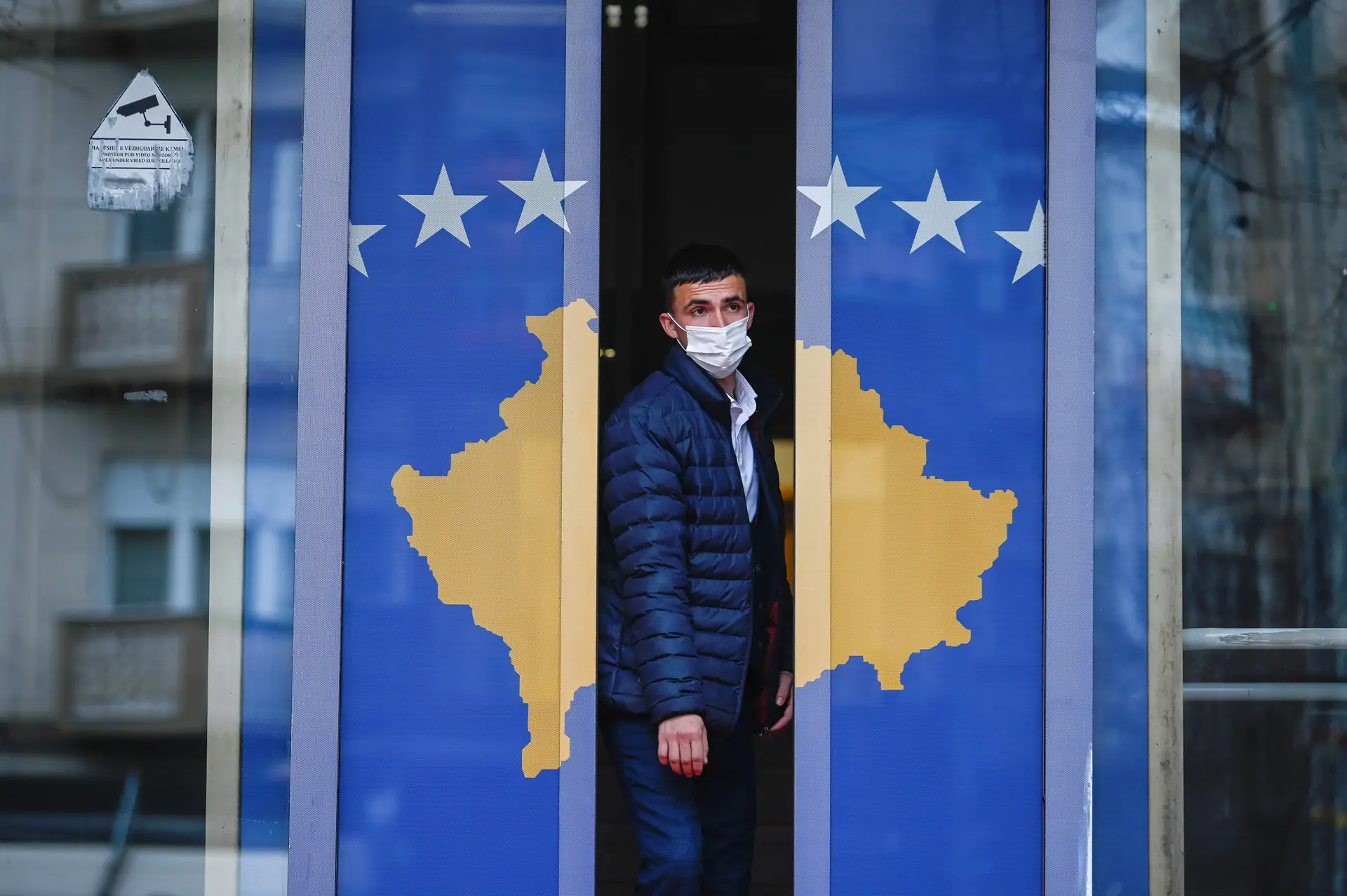 Em Pristina, um homem sai de um edifício governamental, decorado com a bandeira do Kosovo