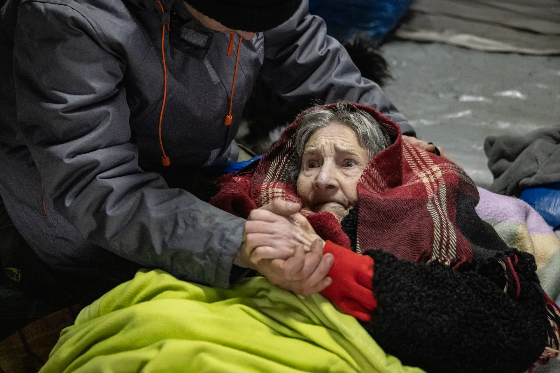 DESORIENTAÇÃO — Uma mão amiga transmite segurança a uma idosa assustada, durante a evacuação de Irpin