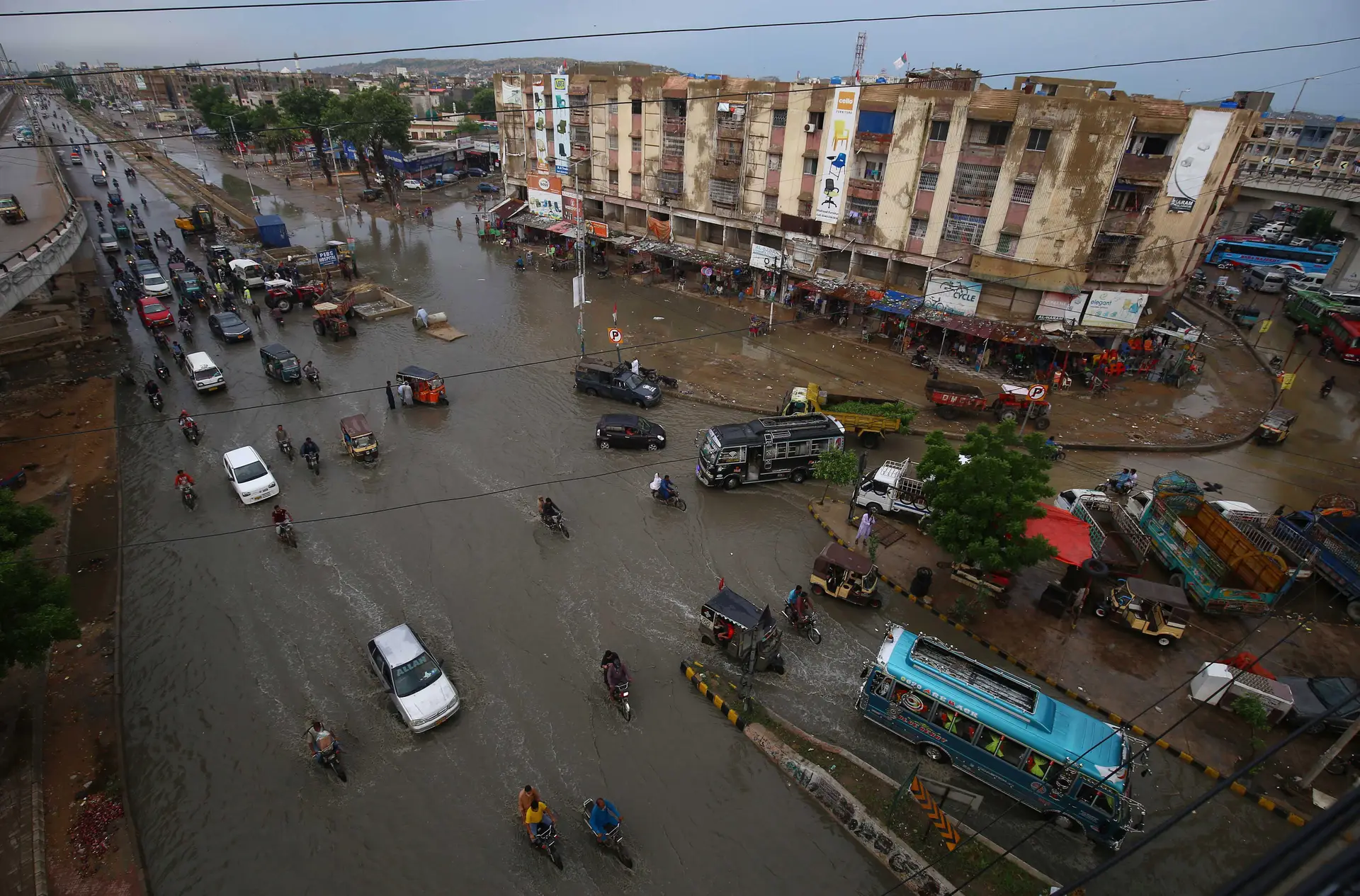 Carros e pessoas atravessam uma área inundada após fortes chuvas em Karachi, a cidade mais populosa do Paquistão, no dia 10 de agosto