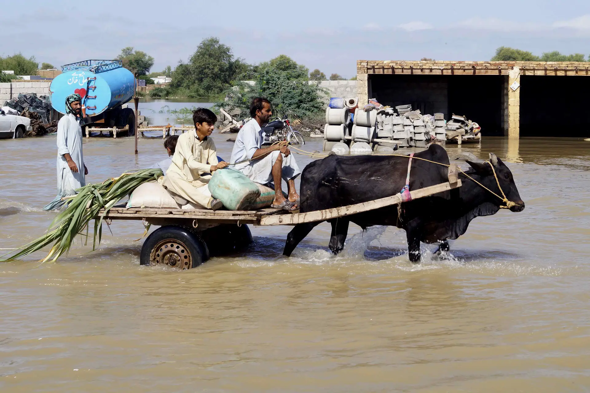 Populares atravessam uma área inundada após fortes chuvas de monção na cidade de Dera Ismail Khan, no Paquistão, a 20 de agosto