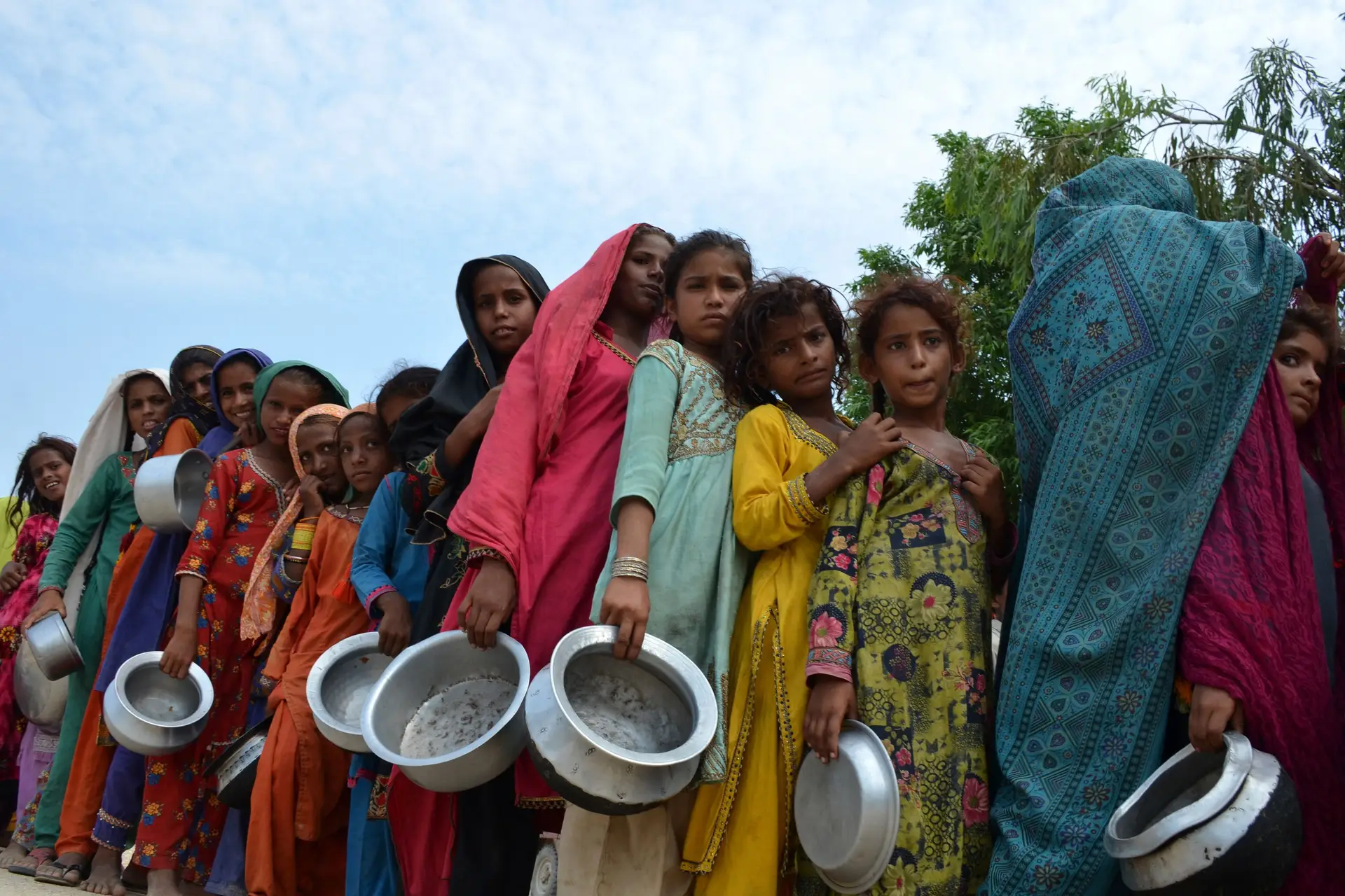 Crianças deslocadas pelas inundações e a viver num campo improvisado aguardam pela distribuição de comida, em Sehwan