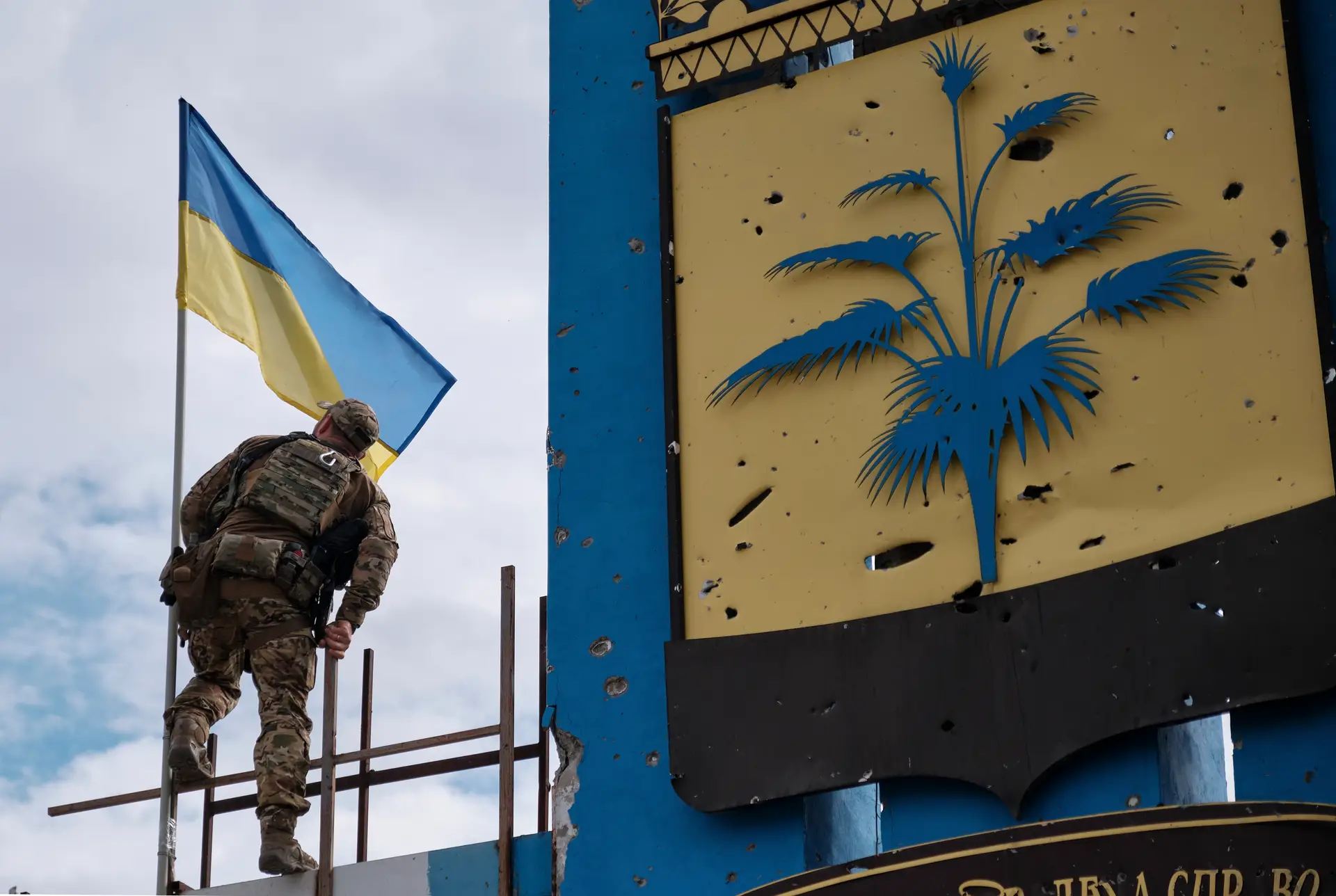 Soldado ucraniano iça a bandeira do seu país perto de Kharkiv. A recuperação de terreno pelos ucranianos leva a Rússia a acelerar supostos referendos nas zonas que pretende anexar