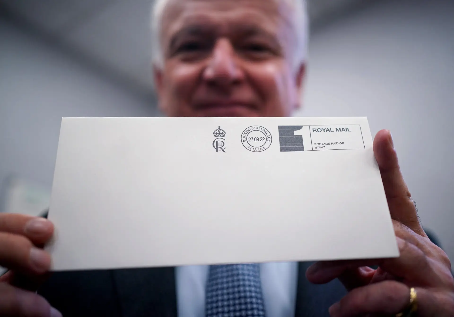 David White, rei de armas da Jarreteira, exibe um envelope com a cifra de Carlos III, impresso a 27 de setembro de 2022 