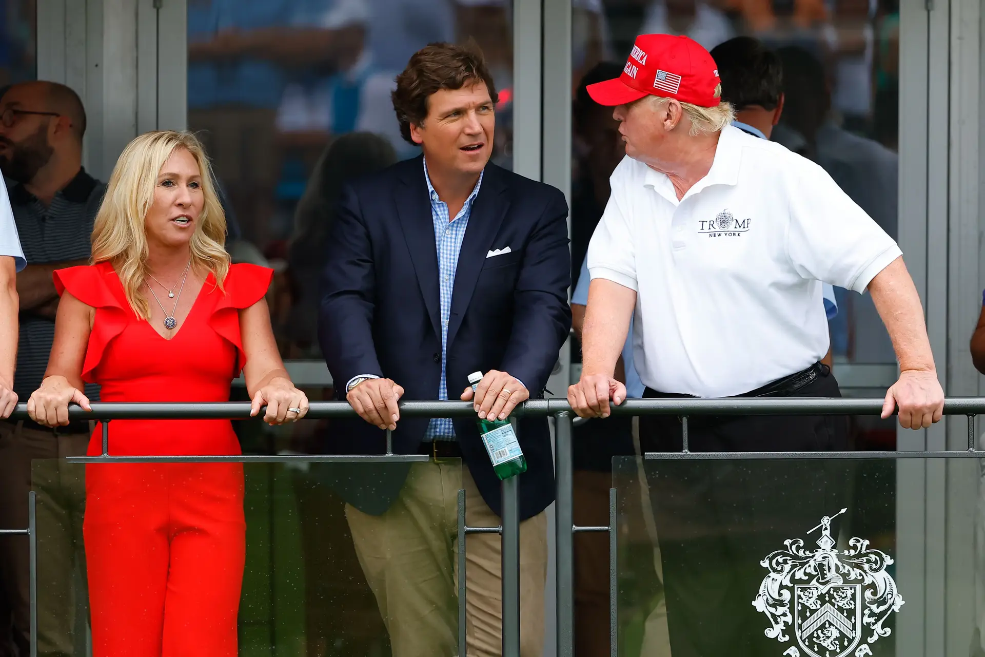 O apresentador de TV Tucker Carlson, ao centro, entre a congressista republicana Marjorie Taylor Greene e o ex-Presidente Donald Trump, durante um torneio de golfe em julho passado