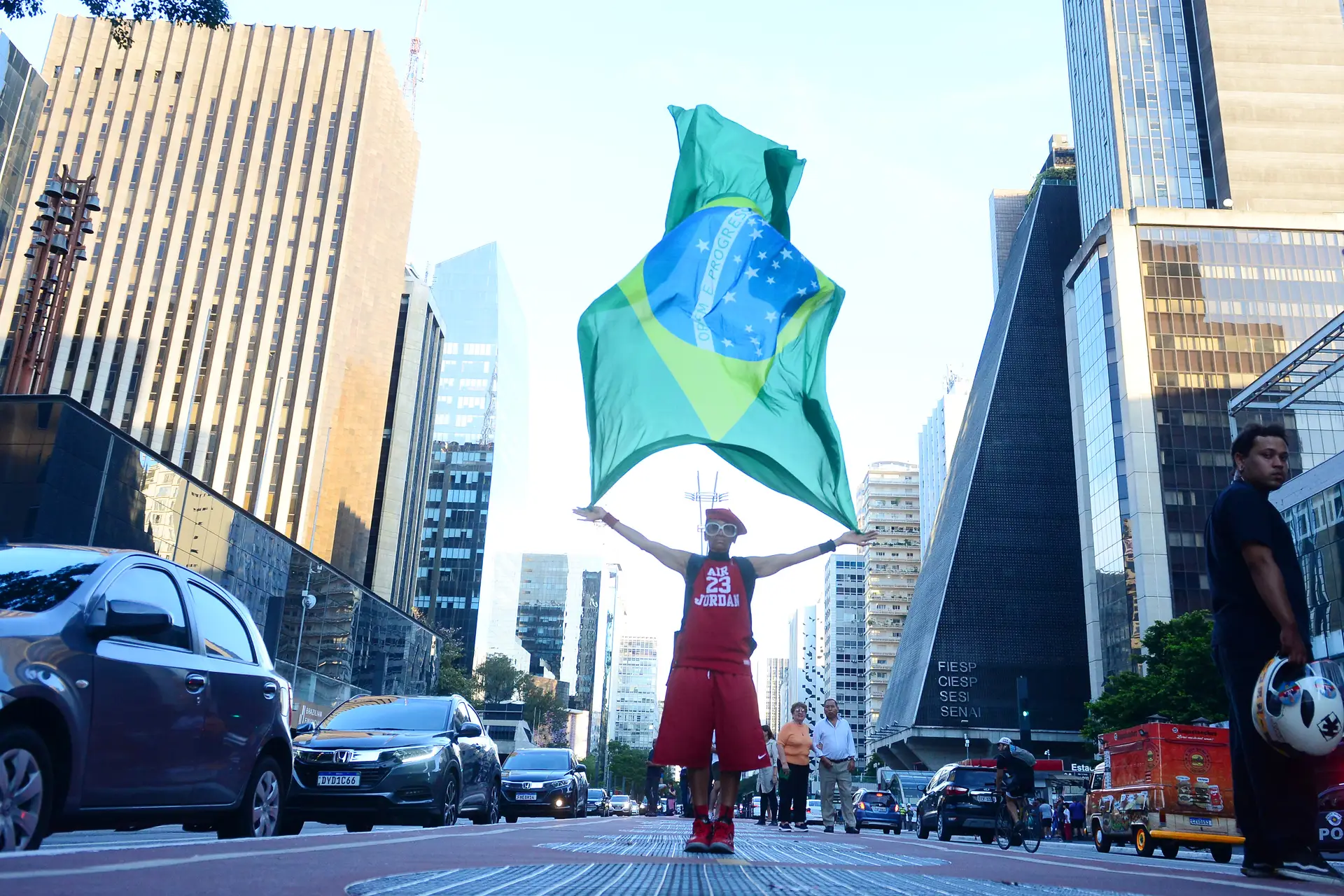 Um homem com uma enorme bandeira do Brasil, já depois do fecho das urnas