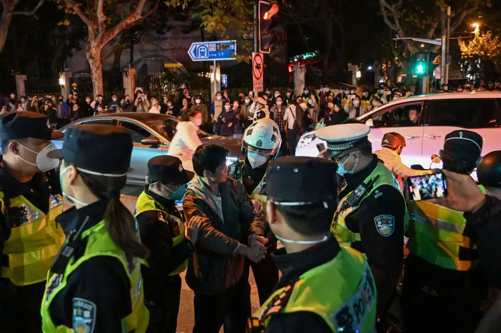 Confrontos com a polícia num protesto na rua Wulumuqi (chamada Urumqi em mandarim), em Xangai este sábado, dia 27 de novembro. As manifestações contra a política 'zero covid' surgem na sequência de um incêndio mortal na província de Xinjiang