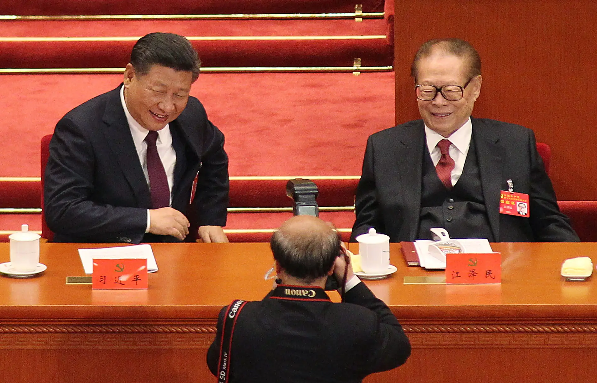 Jiang Zemin (à direita na imagem) sorri para as câmaras ao lado do seu sucessor Xi Jinping, durante o 19.º Congresso do Partido Comunista da China, em 2017