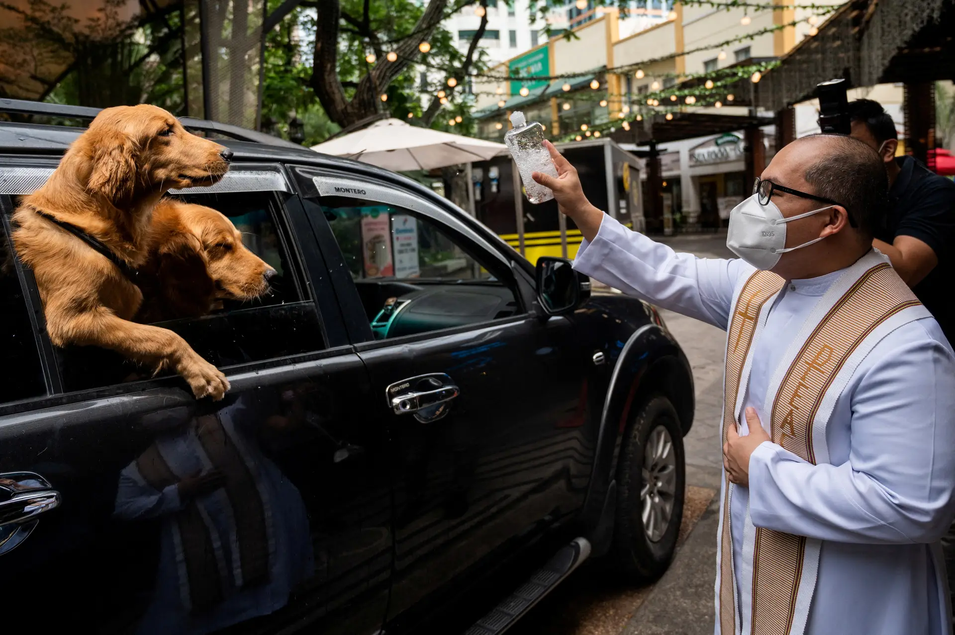 BÊNÇÃO. Um padre borrifa dois cães com água benta, num ‘drive-through’ de Quezon (Filipinas), no Dia Mundial dos Animais